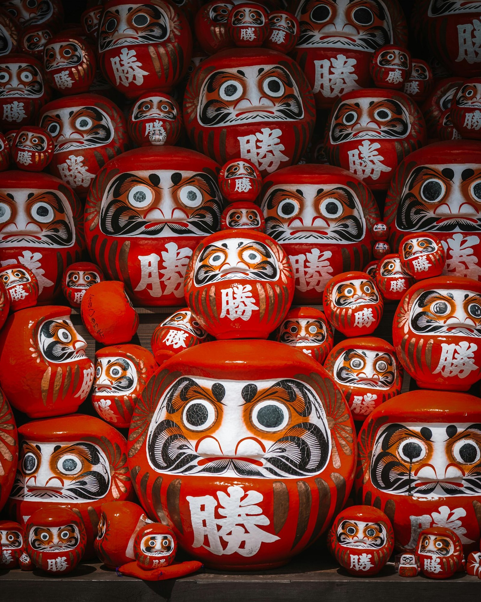A vibrant collection of traditional Japanese Daruma dolls at a market in Osaka, Japan, symbolizing perseverance and good luck.